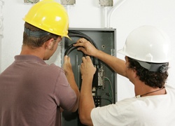 Electricians working together to install a breaker panel. Models are actual electricians - all work is performed according to industry standard code and safety practices.